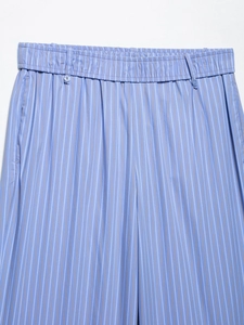 Detailed close-up of the elastic waistband and button accents on blue striped cotton trousers