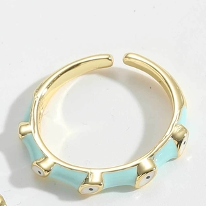 Macro detail of gold-plated Evil Eye ring featuring light blue enamel and adjustable band
