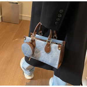Detail of blue denim and brown leather tote bag with small matching round purse charm