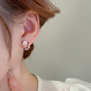 Dettaglio di orecchini a fiore con strass rosa e bianchi indossati da una modella
