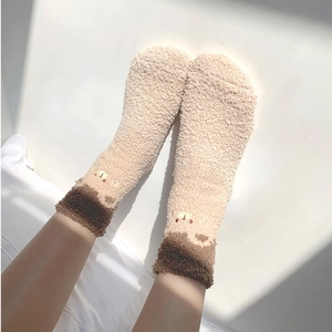 Detailed texture of warm coral fleece socks featuring a cute bear embroidery accent