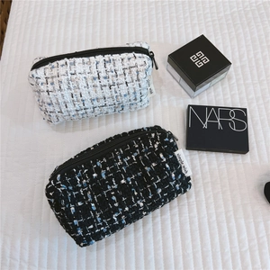 Detail of tweed makeup bags in black and white with zipper and simple wish label