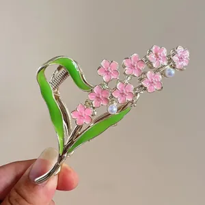 Detailed close-up of a hand-painted floral hair claw with pink oil drip heart and pearls
