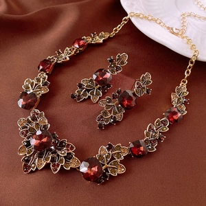 Detail view of vintage leaf jewelry set with red gems on brown silk fabric