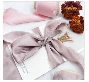 Detail of frayed edge satin ribbons in soft pink and dusty purple for gift wrapping