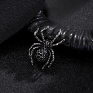 Macro shot of gothic spider brooch with black rhinestones on dark textured background