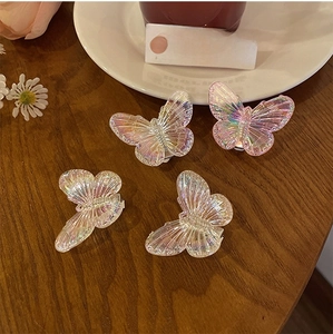 Detailed view of iridescent butterfly hair clips on a wooden surface with a soft glow