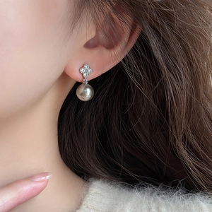 Gros plan de boucles d'oreilles fleur en argent avec perles grises et zircons