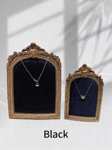Retro jewelry display with gold frames and necklaces against black velvet backdrop