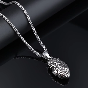 Collier avec pendentif cœur anatomique en acier inoxydable sur surface noire brillante