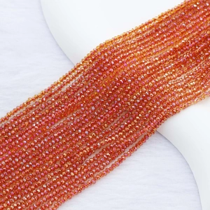 Macro view of 2mm orange faceted crystal beads on soft white texture for jewelry DIY