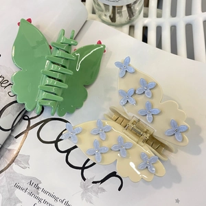 Detail of green and beige butterfly hair claws with blue flowers and crystal rhinestones