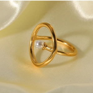 Macro detail of 18k gold plated ring with a round pearl on elegant yellow silk fabric