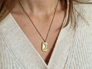 Detailed close-up of a 18k gold plated moon pendant necklace worn by a female model