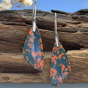 Bohemian teardrop turquoise earrings with silver metal hooks on natural wood background