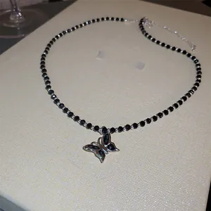 Détail du collier de perles noires avec pendentif papillon argenté et pierres précieuses
