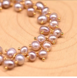 Macro shot of lustrous pink pearls and gold metal links on a warm wood background