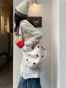 Close-up of white plush tote bag with red heart embroidery and faux shearling texture