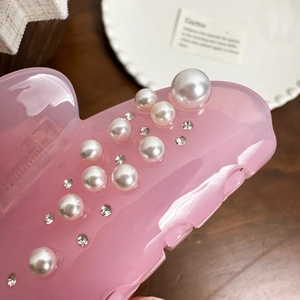 Pink acetate claw clip with white pearls and rhinestones in a professional macro shot