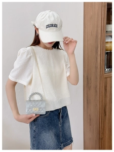 Detail of transparent jelly bag with beaded handle and golden chain shoulder strap