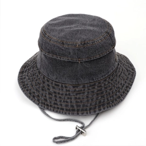 Detail of grey washed denim sun hat featuring metal logo patch and adjustable drawstring