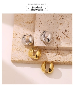 Detailed view of chunky gold and silver dome earrings on a natural stone base