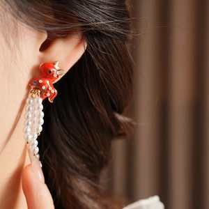 Detail of vintage red enamel fish earring with white pearl tassels on a model