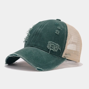 Detail of vintage distressed baseball cap featuring green canvas with ripped edges and mesh back