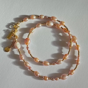 Detail of pink baroque pearls and gold beads necklace with metallic clasp and extender chain