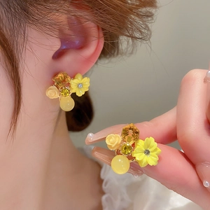 Detailed close-up of yellow floral earrings with opal-like resin petals and crystal centers