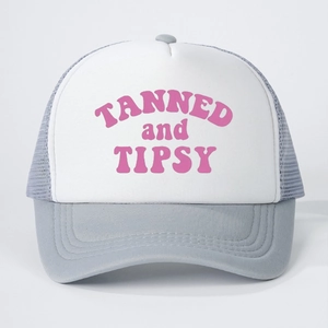 Detail of grey mesh trucker hat with pink TANNED and TIPSY text and curved brim