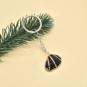 Detail of bohemian shell keychain with gold-edged black pendant and silver metal ring