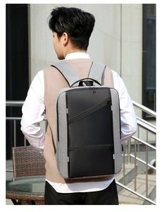 Man wearing modern minimalist grey business laptop backpack with USB port outdoors