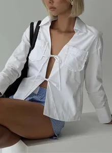Détail de chemise blanche avec fermeture à lacets et poche à volants et short rayé