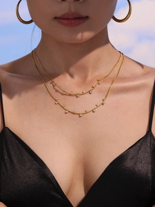 Détail d'un mannequin portant un collier double rang en or avec des breloques en zircone