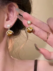 Detail of vintage 18K gold plated pearl earrings with brown cat-eye stone beads