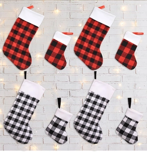 Detail of red and black buffalo plaid Christmas stockings on a brick wall with fairy lights