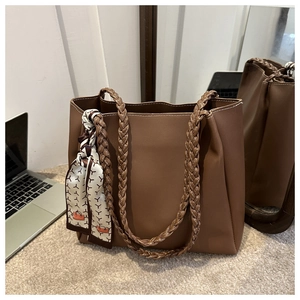 Détail d'un grand sac cabas en cuir marron avec anses tressées et foulard décoratif chic