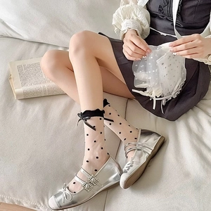 Détail de chaussettes transparentes à pois avec babies argentées et joli nœud