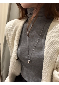 Close-up of a silver irregular water drop pendant necklace on a grey sweater