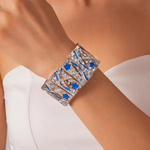 Detailed view of wide silver metal bracelet with blue enamel stars and inlaid blue stones