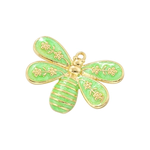 Macro view of a gold dragonfly pendant featuring sparkling green enamel wings