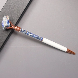 Detail of rose gold metal ballpoint pen featuring blue crystal stones in a clear tube