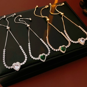 Close-up of heart zircon adjustable bracelets in gold and silver on black leather