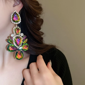 Close-up of a model wearing large colorful rhinestone teardrop dangle earrings in gold
