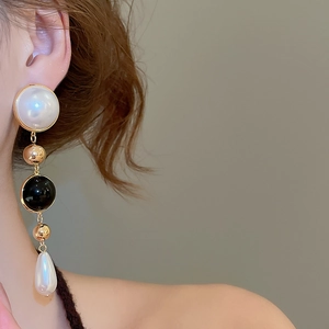 Detail of elegant gold layered drop earrings with white pearls on a female model
