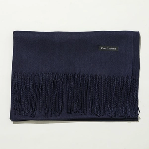 Detailed texture of dark blue cashmere scarf featuring soft fringes and a material tag