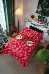 Close-up detail of red Christmas tablecloth featuring white snowflake prints and holiday decor