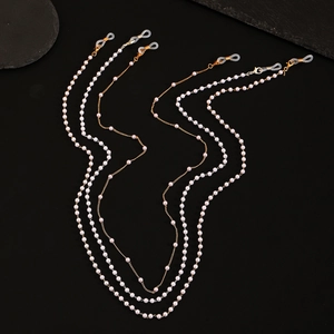 Détail de chaînes de lunettes élégantes en perles blanches avec maillons dorés