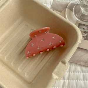 Detail of pink double-sided rhinestone hair claw clip in a rustic paper gift box